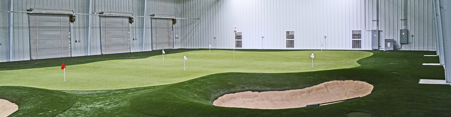 Indoor artificial turf golf facility with multi-hole putting green and sand bunker installed by Southwest Greens